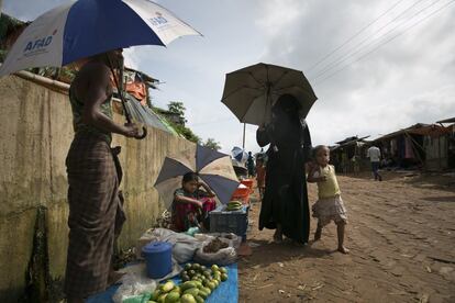 Una mujer camina con una niña junto a vendedores de comida en el mercado de refugiados Kutupalong en Cox's Bazar (Bangladés). Cox's Bazar es el campo de refugiados más grande y densamente poblado del mundo. De su casi un millón de residentes, más de la mitad son niños. La mayoría de las personas aquí son rohingya, un grupo perseguido, predominantemente musulmán y una minoría de Myanmar, que ha sufrido discriminación en su país durante varias décadas, incluyendo la denegación de la ciudadanía.