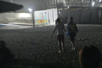 Un par de menores marroquíes que acaban de llegar a nado a la playa del Tarajal, salen caminando hacia la ciudad, en la noche de este viernes. 