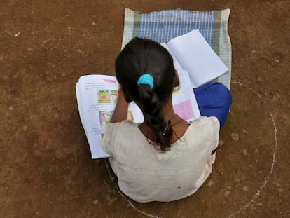 Una niña, que se ha perdido sus clases en Internet debido a la falta de conexión, se sienta en el suelo dentro de un círculo para mantener una distancia segura mientras escucha lecciones pregrabadas, en Dandwal, Maharashtra (India).