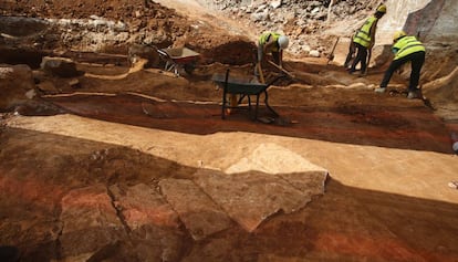 Una de les 16 tombes ja excavades, en primer pla. Al fons, tres arqueòlegs treballen en una altra de les fosses.