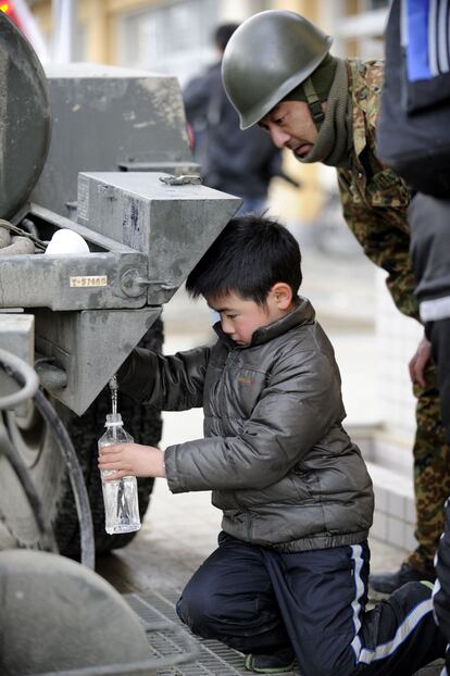 Un niño recoge agua de un depósito del Ejército japonés en la ciudad de Rikuzentakata, en la prefectura de Iwate.