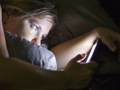 Una mujer enreda con su móvil en la cama, un acto nada recomendable según los expertos en sueño