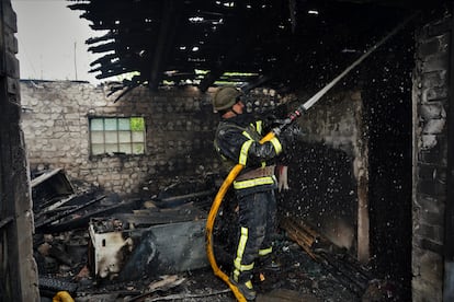 Firefighters put out a fire in a house hit by a Russian missile.