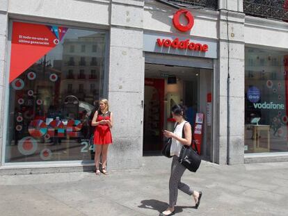 Usuaria de m&oacute;vil frente a una tienda Vodafone