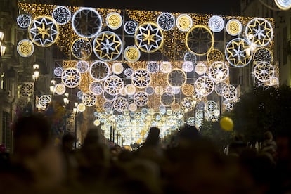 La gente pasea bajo las luces de Navidad en el centro de Sevilla.