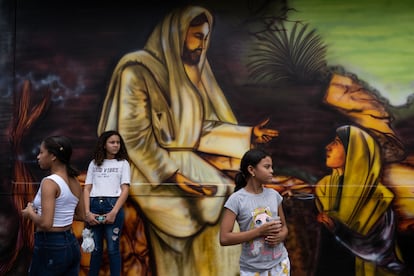 Niñas ven pasar la procesión de los penitentes al lado de uno de los 31 murales religiosos que hay en el municipio de San Diego.
