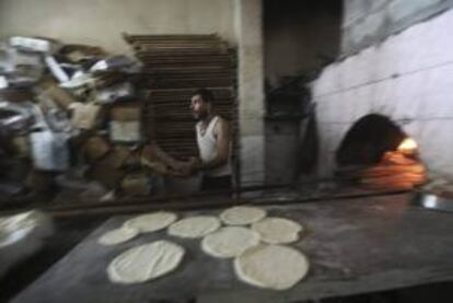 Un hombre palestino prepara unos panes en un horno tradicional hoy durante la celebración del mes sagrado del Ramadán, en el campamento de refugiados de Jabalya, norte de la franja de Gaza.