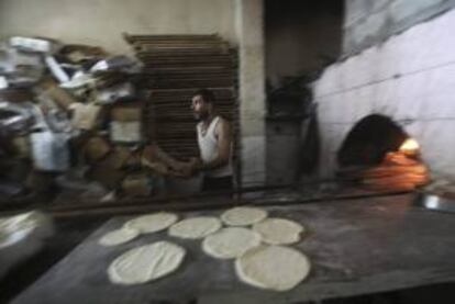 Un hombre palestino prepara unos panes en un horno tradicional hoy durante la celebración del mes sagrado del Ramadán, en el campamento de refugiados de Jabalya, norte de la franja de Gaza.