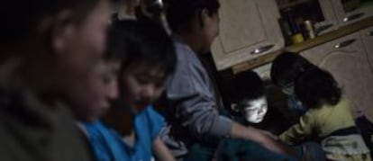 Hijos y amigos de Damb Batnasan juegan con los dos teléfonos inteligentes de la familia a la luz de la bombilla de bajo consumo que tienen conectada a una batería.