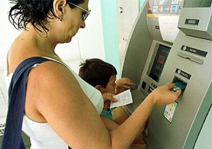 Una mujer saca dinero de un cajero automático