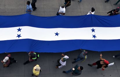 Maestros, doctores y estudiantes ondean una bandera de Honduras.