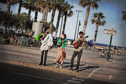 Tres personas tocan en la calle del paseo marítimo de Valencia frente a la playa del Cabanyal.
