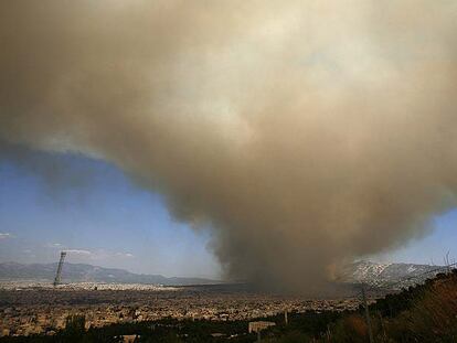 Una nube de humo provocada por el incendio sobre la montaña Pendelis se extiende ayer sobre Atenas.