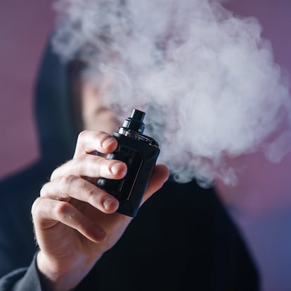 Close-up of an electronic cigarette and a man exhaling steam