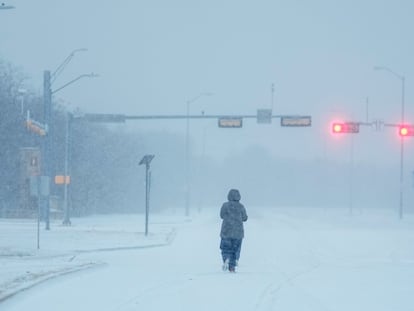 A jogger trots on a snow-covered road during a winter storm, Monday, Jan. 15, 2024, in Grand Prairie, Texas.