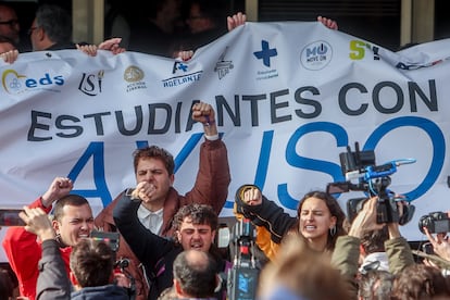 Varios estudiantes intentan tapar una pancarta a favor de la presidenta de la Comunidad de Madrid.