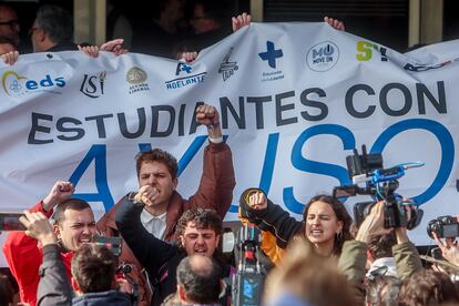 Varios estudiantes intentan tapar una pancarta a favor de la presidenta de la Comunidad de Madrid.