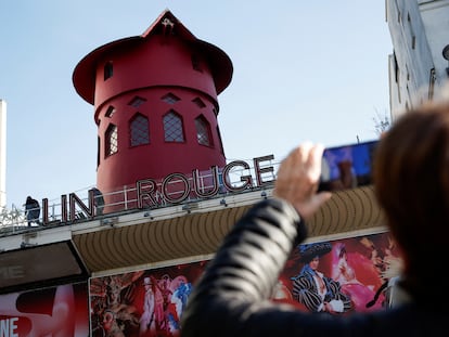 People take pictures of the landmark red windmill atop the Moulin Rouge, Paris' most famous cabaret club, after its sails fell off during the night in Paris, France, April 25, 2024. REUTERS/Benoit Tessier