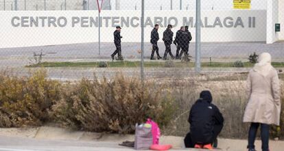 Un grupo de agentes pasea junto a la carcel de Archidona, bajo la mirada de varios familiares de los inmigrantes internados.