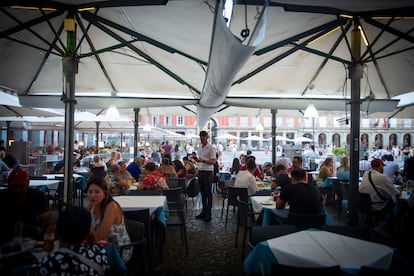 Un camarero, en el centro de la imagen, atiende a unos clientes en la Plaza Mayor de Madrid, este jueves.