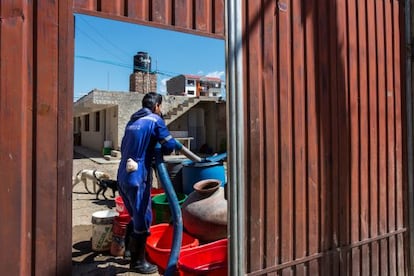 Un operario llena barriles con agua de camiones.