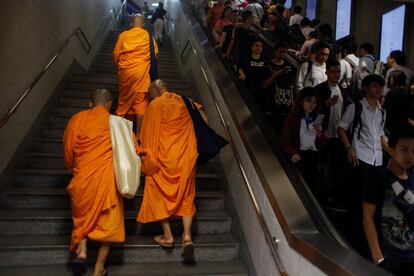 Monjes budistas y viajeros en el metro de Bangkok (Tailandia).