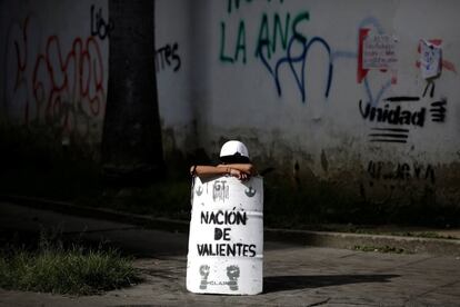 Un manifestante se apoya en un escudo casero donde se puede leer 'Nación de valientes'.