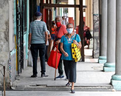 Personas, con mascarilla, caminan por las calles de La Habana.