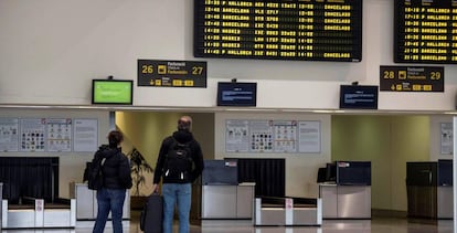 Dos pasajeros comprueban sus vuelos en el aeropuerto vacío de Menorca, en Mahón, este jueves.