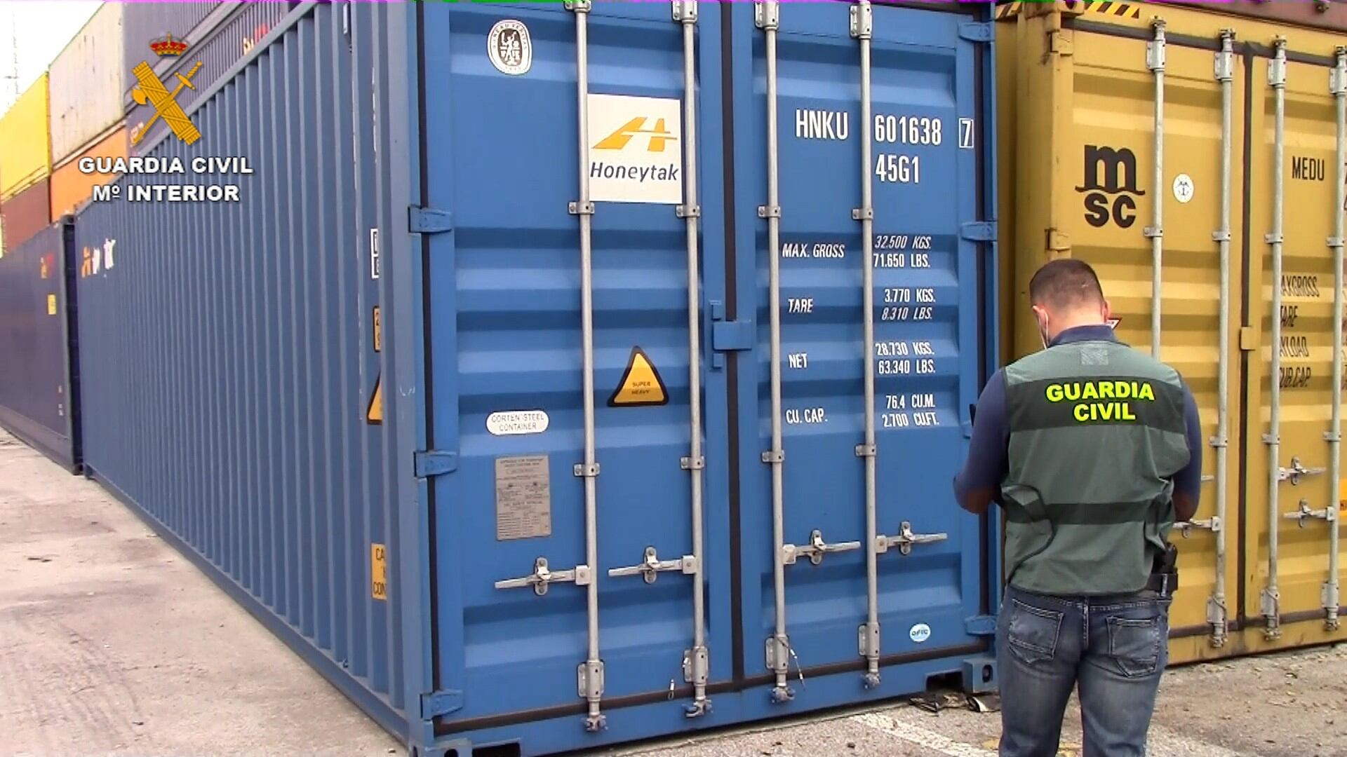 Un agente de la Guardia Civil inspecciona un contenedor de residuos. 