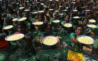 Un grupo de mujeres indias posan mientras sostienen platos de pétalos de flores, en una ofrenda durante una ceremonia para las víctimas del tsunami de 2004, en la playa de Pattinapakkam, en Chennai. 