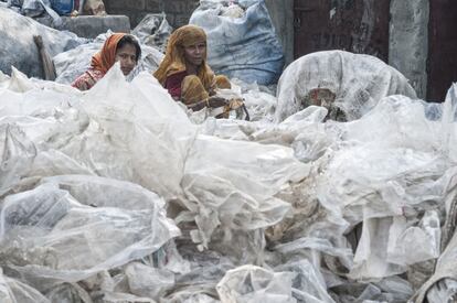 Son sobre todo mujeres y niños quienes llevan a cabo la minuciosa tarea de clasificar los diferentes tipos de plástico antes de que sean procesados en las pequeñas plantas situadas a orillas de un río de Dacca, (Bangladés).