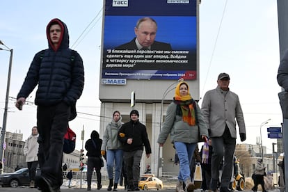 Varias personas pasan junto a una pantalla con el discurso de Vladímir Putin, este jueves en Moscú. 