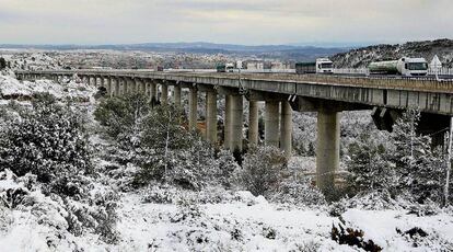 Varios camiones en el viaducto de Buñol junto a un paisaje nevado a solo 40 kilómetros de la ciudad de Valencia.