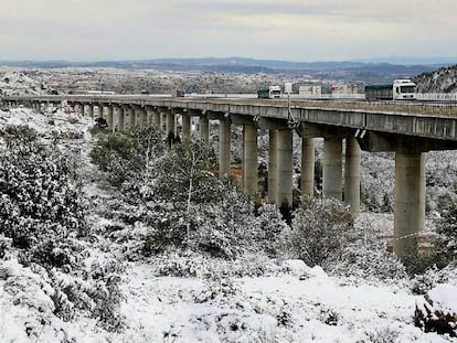 Varios camiones en el viaducto de Buñol junto a un paisaje nevado a solo 40 kilómetros de la ciudad de Valencia.