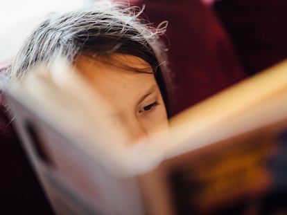 Una niña lee con atención un libro.