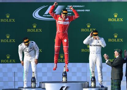 El piloto Sebastian Vettel (c) de la escudería Ferrari celebra su victoria en el pódium junto con Lewis Hamilton (izquierda) y Valtteri Bottas, en segunda y tercera posición.