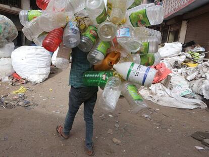 Un trapero carga a su espalda con botellas y bidones de plástico en las calles de la ciudad india de Bhopal, el pasado junio.
