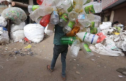 Un trapero carga a su espalda con botellas y bidones de plástico en las calles de la ciudad india de Bhopal, el pasado junio.