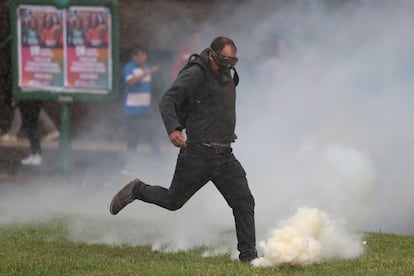 Un hombre patea una granada de gas lacrimógeno para alejarla de los manifestantes. 