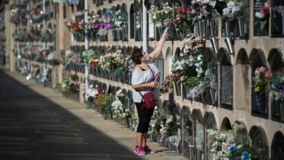 Una mujer deposita flores en un nicho del cementerio del Poblenou, Barcelona.