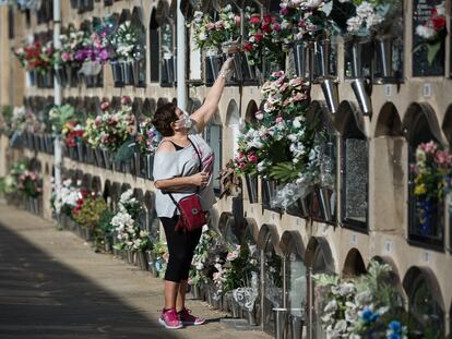 Una mujer deposita flores en un nicho del cementerio del Poblenou, Barcelona.