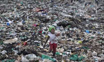 Joyce Njeri, de ocho años, lleva un saco desgarrado con las botellas de plástico que ha recogido mientras camina entre basura y bolsas de plástico en el vertedero del barrio de Dandora de Nairobi, Kenia.