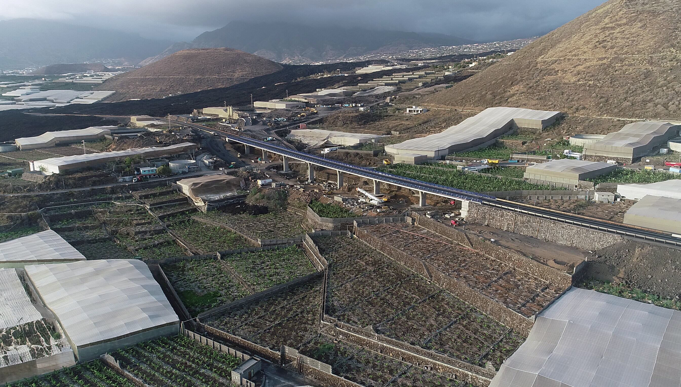 El viaducto de la nueva carretera a la costa, detrás de la Montaña de Todoque. Al fondo, la Montaña de La Laguna.