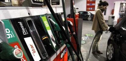 Una mujer pone combustible a su vehículo.