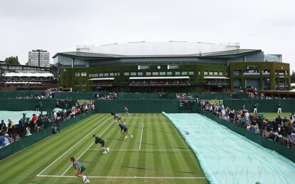 El gran torneo inglés, que comenzó el lunes 27, recobra toda su esencia y festeja el centenario de la majestuosa Centre Court, donde abrió el serbio Novak Djokovic, imbatible desde 2018. En la foto, las cubiertas de lluvia se tiran sobre la pista mientras la lluvia retrasa el juego.