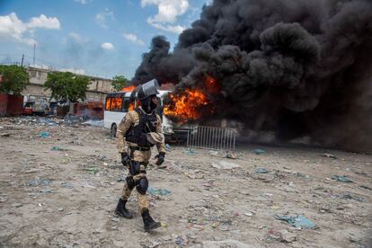 Un policía pasa cerca de un bus que arde en llamas, en Puerto Príncipe (Haití). Decenas de manifestantes realizaron una protesta dentro y fuera la sede legislativa para tratar de boicotear la sesión en la que está previsto votar la ratificación del nuevo primer ministro, Fritz William Michel, y su Gobierno.