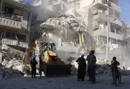 Civiles de Alepo observan cómo una pala mecánica retira escombros.