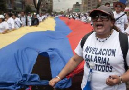 Trabajadores del sector de la justicia de Colombia sosteniendo una bandera de Colombia durante una marcha el pasado 26 de octubre, para reclamar una nivelación salarial. EFE/Archivo