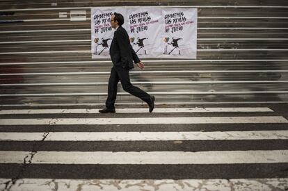 Un hombre pasa delante de un cartel electoral de Podemos bajo el lema 'Cambiemos las reglas de juego', en una calle de Pamplona (Navarra).